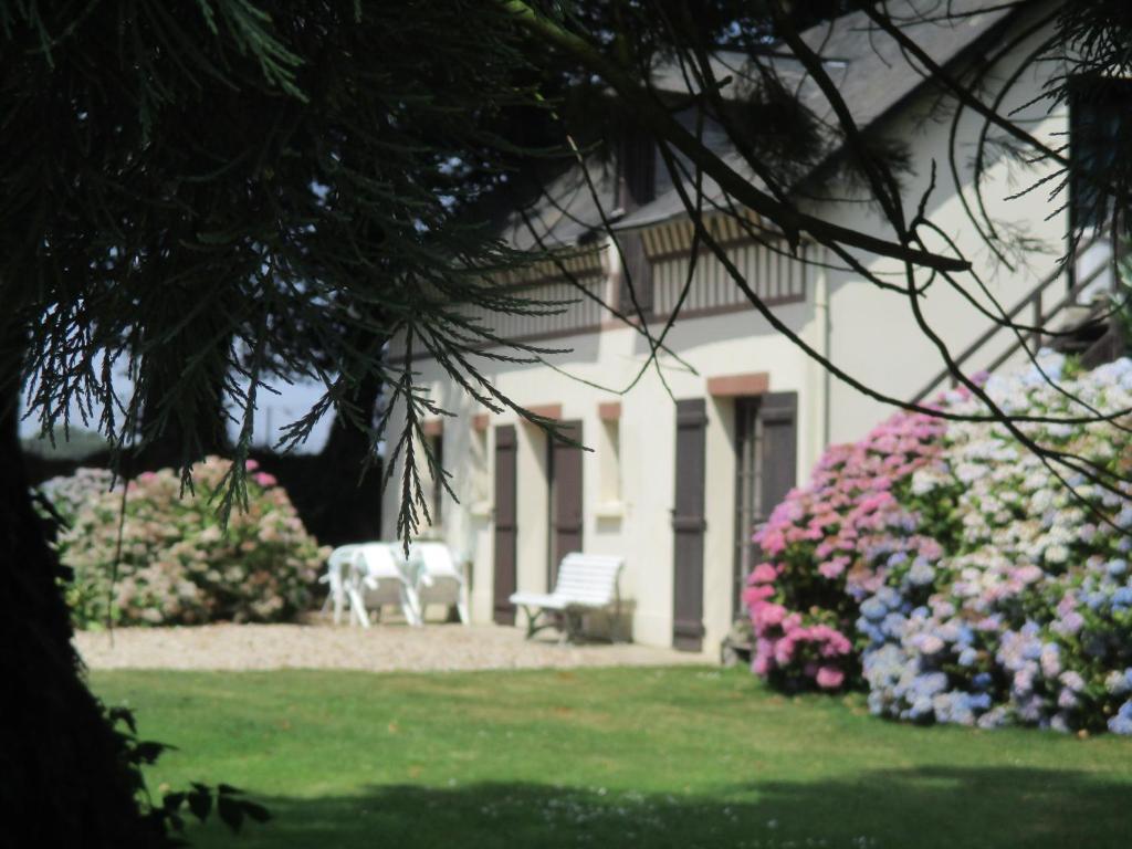 une maison blanche avec un banc et quelques fleurs dans l'établissement LA HETRAIE, à Vergetot