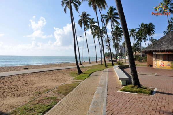 un trottoir à côté d'une plage bordée de palmiers dans l'établissement Apt Jatiúca, Excelente Localização.balada, Praia.., à Maceió