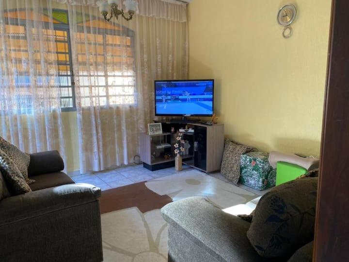 een woonkamer met een bank en een flatscreen-tv bij Casa do Descanso em São Bento do Sapucaí in São Bento do Sapucaí