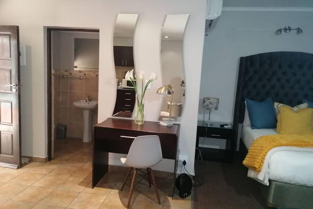 a bedroom with a desk and a bed and a mirror at BEAUTIFUL APARTM B10 SITUATED IN BAINS GAME LODGE in Bloemfontein