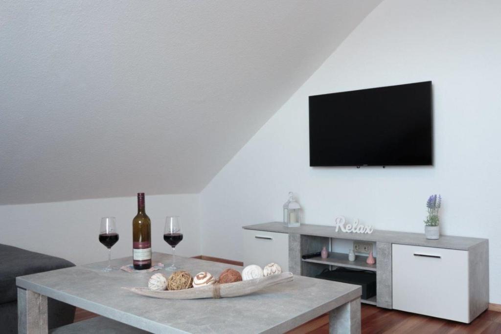 a living room with a table with a tv and wine glasses at Ferienwohnung Grauschiefer in Irsch