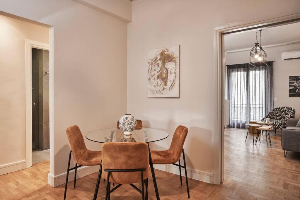 a dining room with a glass table and chairs at Ilisia Park Contemporary 2BD Condo in Athens