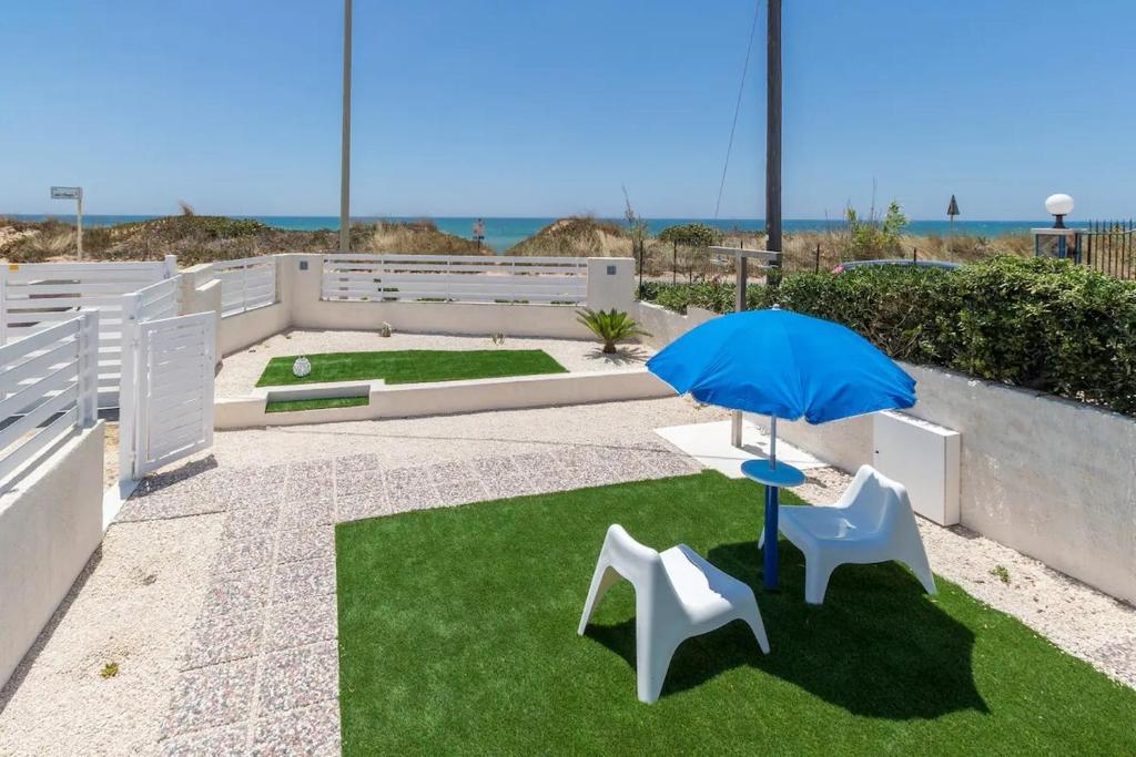 a patio with a table and two chairs and an umbrella at Villa Oneiro Fronte Mare in Santa Maria Del Focallo