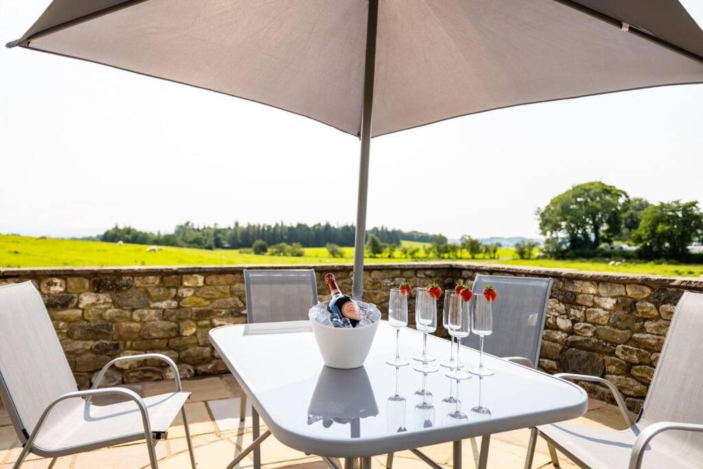 a white table with wine glasses and an umbrella at Cosy cottage between the Lakes and Dales in Cowan Bridge