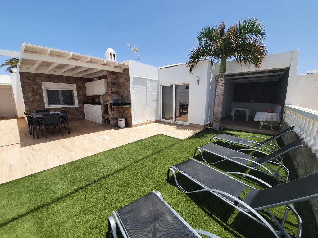 a patio with lawn chairs and a table and a house at Bungalow Aries in Tías