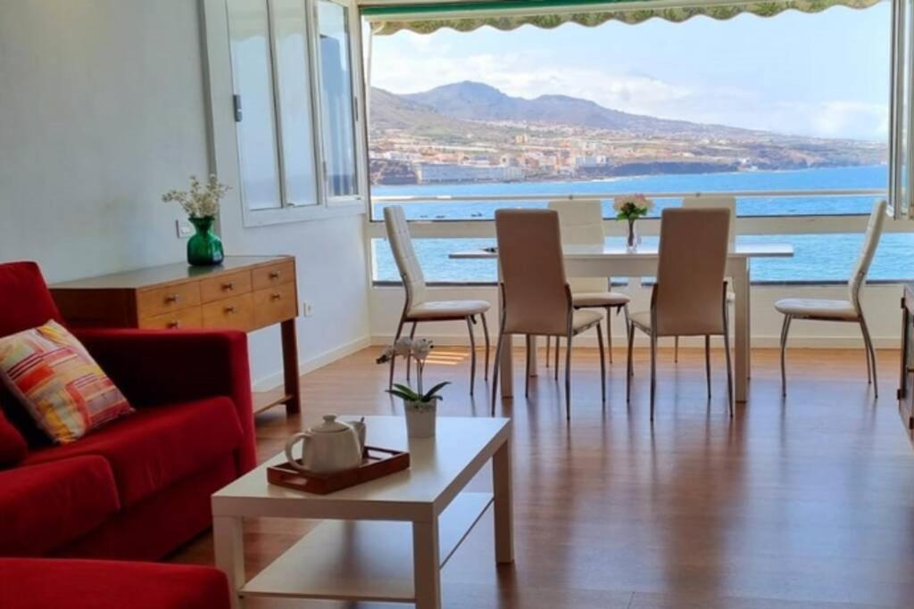 sala de estar con sofá rojo, mesa y sillas en AguaMarina, en Punta del Hidalgo