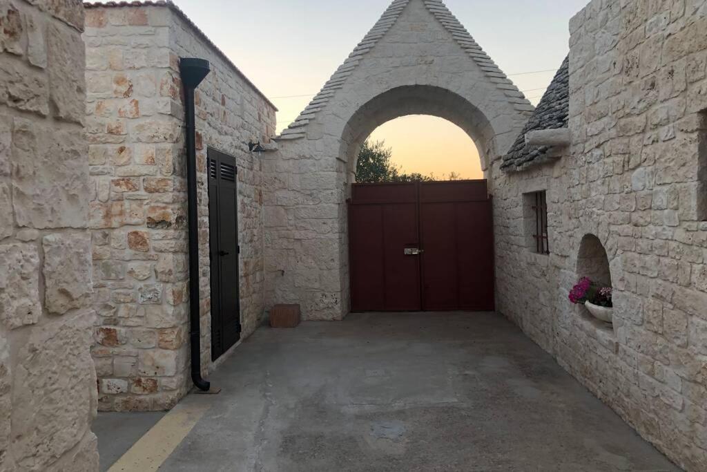 uma entrada para uma garagem com uma porta de garagem vermelha em Masseria Mezza Ruota 2 em Alberobello