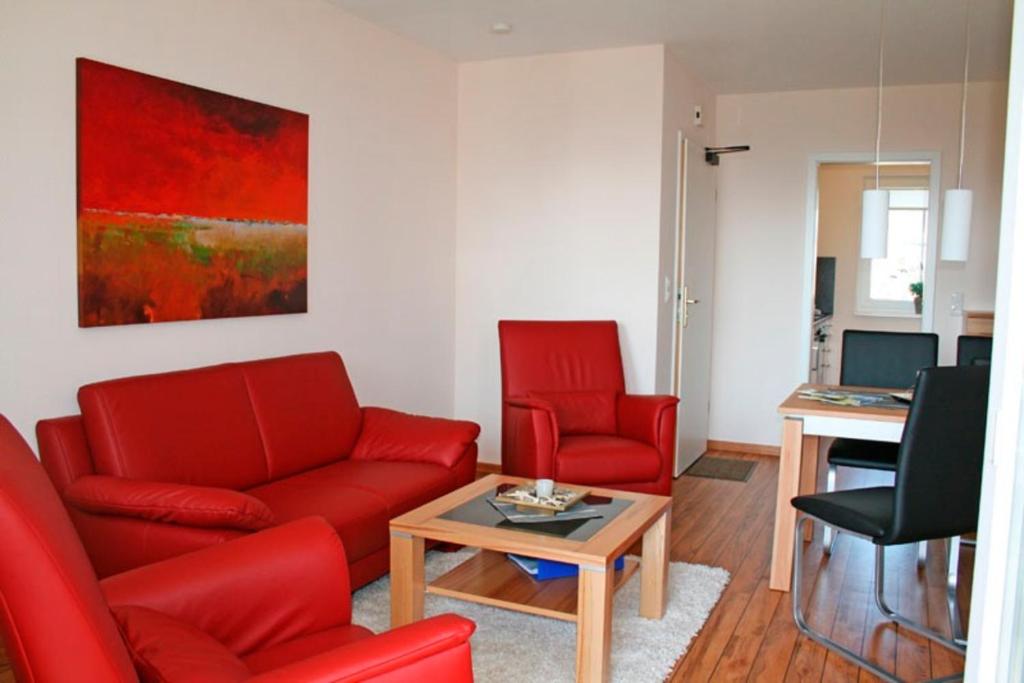 a living room with a red couch and two chairs at "Landhaus Voss" Typ 2 Nr6 in Staberdorf