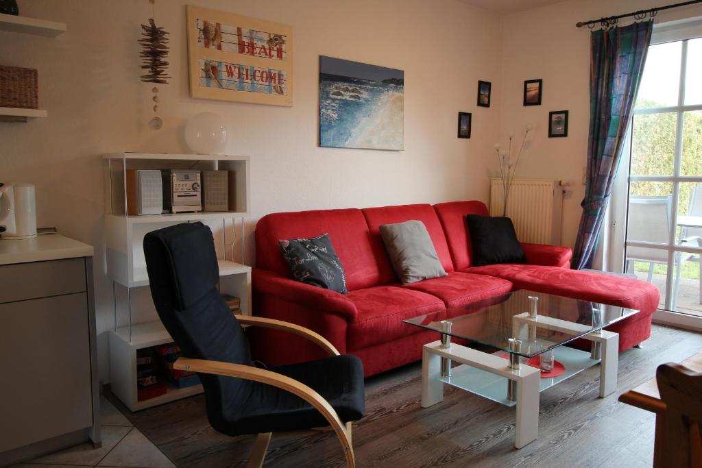 a living room with a red couch and a glass table at Haus am Bodden in Zingst