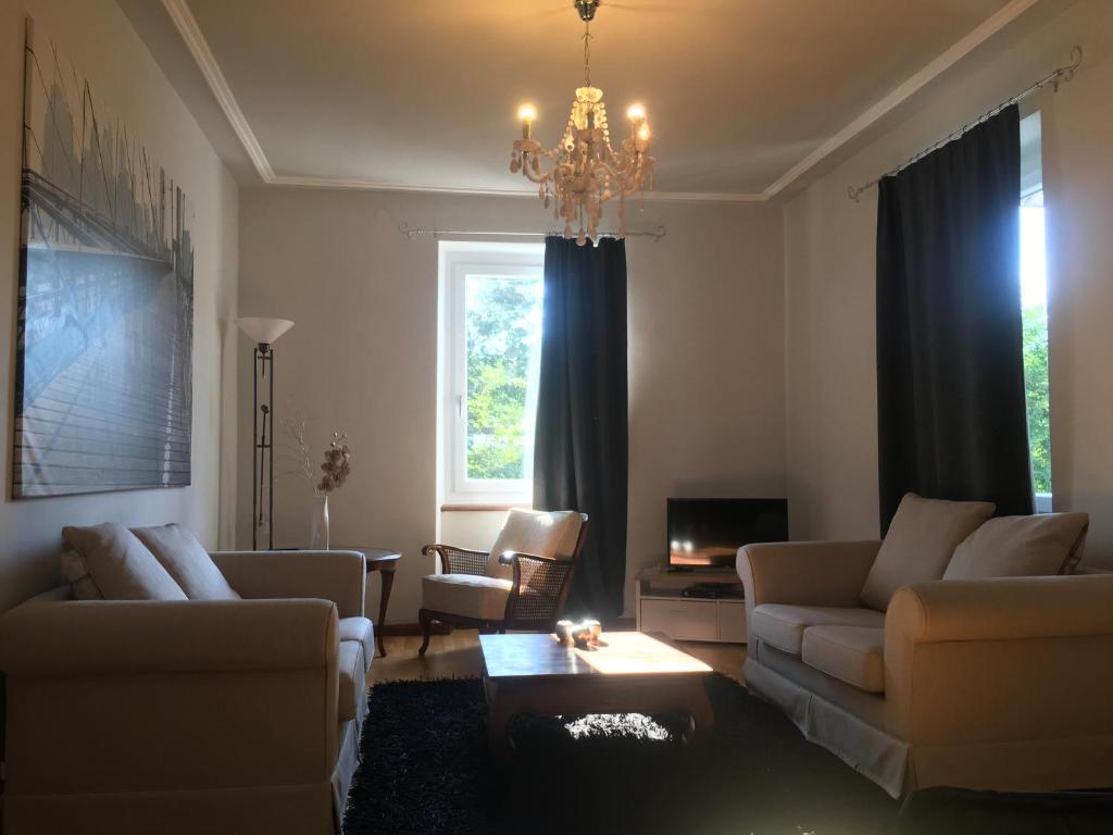 a living room with couches and a chandelier at WALDSHUT SUITE IN ZENTRUM in Waldshut-Tiengen