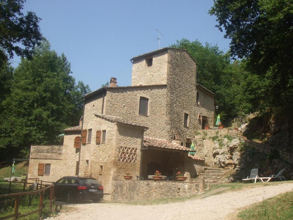 a stone building with a car parked in front of it at Podere il Vecchio Mulino in San Gimignano