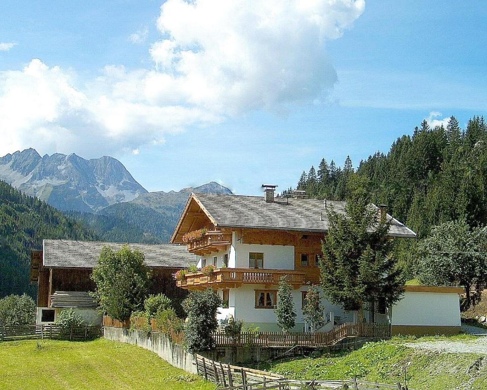 a large wooden house with mountains in the background at Haus Sonnleiten in Gerlos