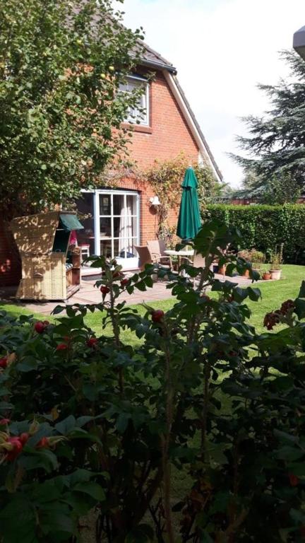 a house with a garden with a patio and an umbrella at Apfelgarten in Boldixum
