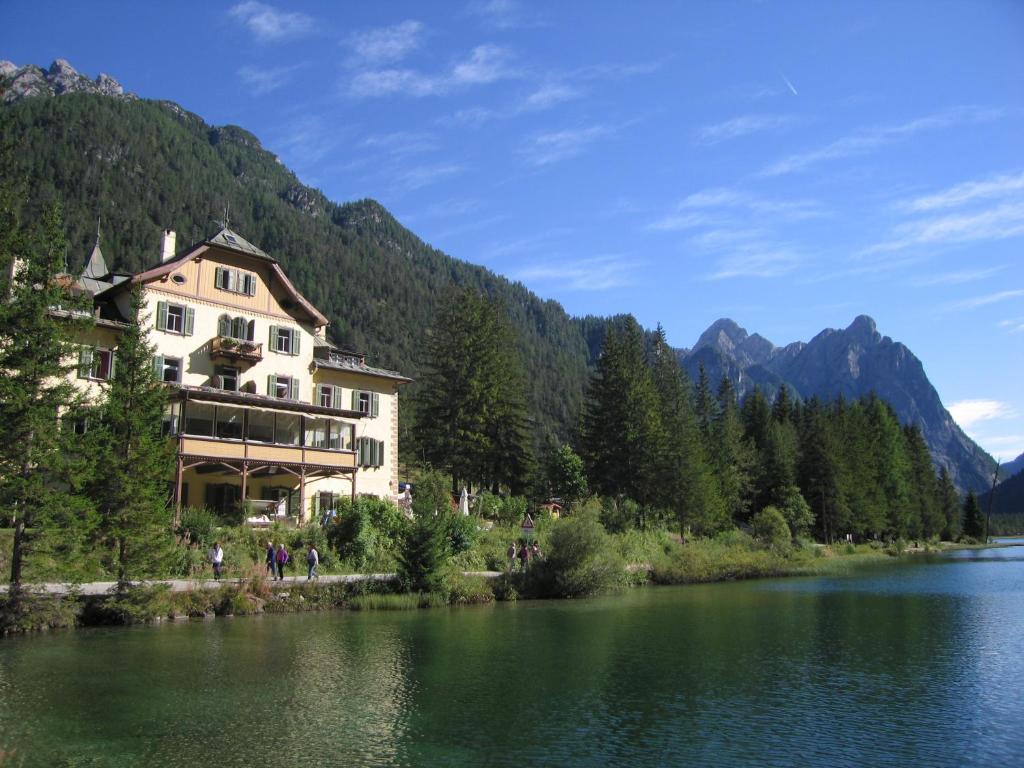 un grand bâtiment au bord d'un lac dans l'établissement Hotel Baur Am See, à Dobbiaco