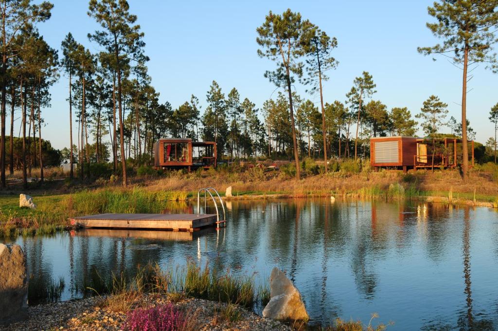 a view of a lake with two houses and trees at Cocoon Eco Design Lodges in Comporta