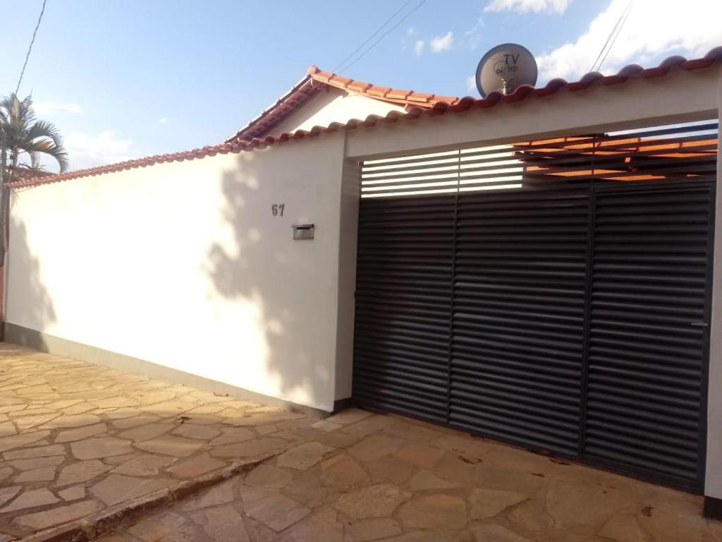 ピレノポリスにあるCasa 57 Temporadaの白い家の黒いガレージドア付きガレージ