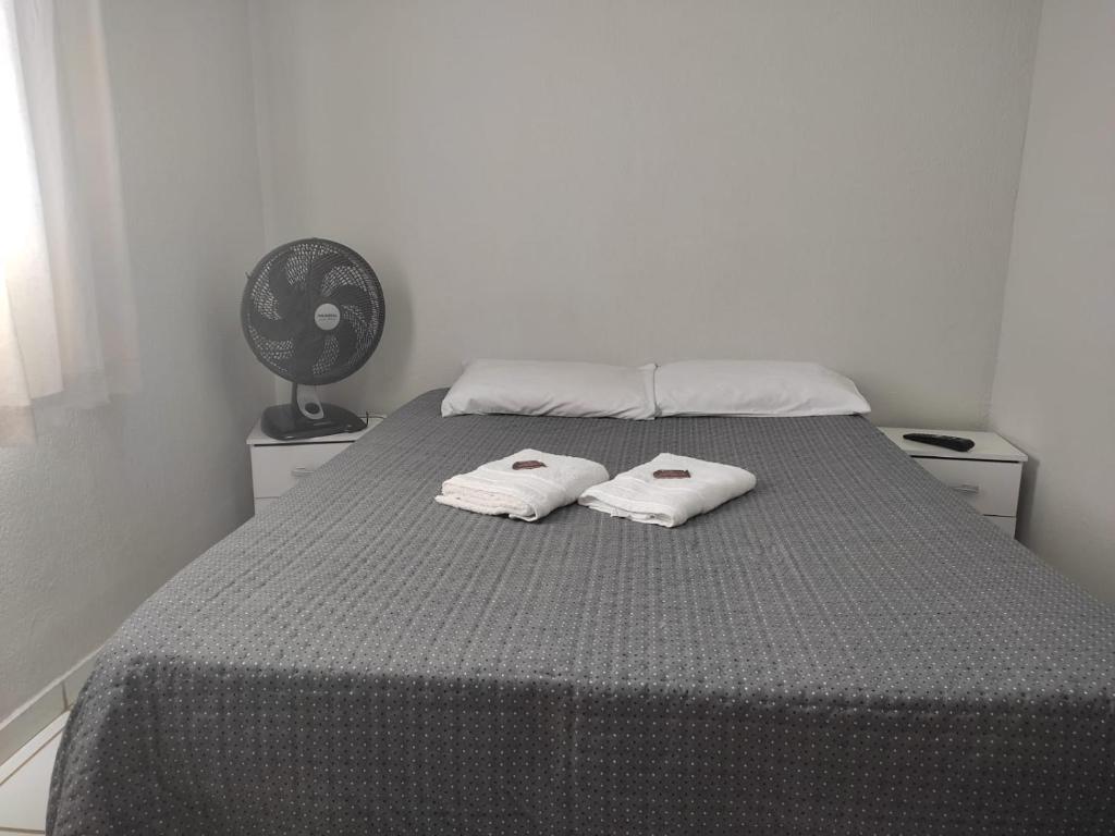 a bedroom with a bed with two towels on it at Apto com estacionamento, piscina e churrasqueira in Bragança Paulista