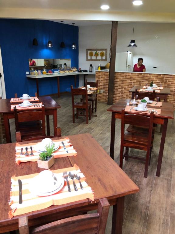 a restaurant with wooden tables and chairs and a kitchen at Pousada Ciclo do Ouro in Paraty