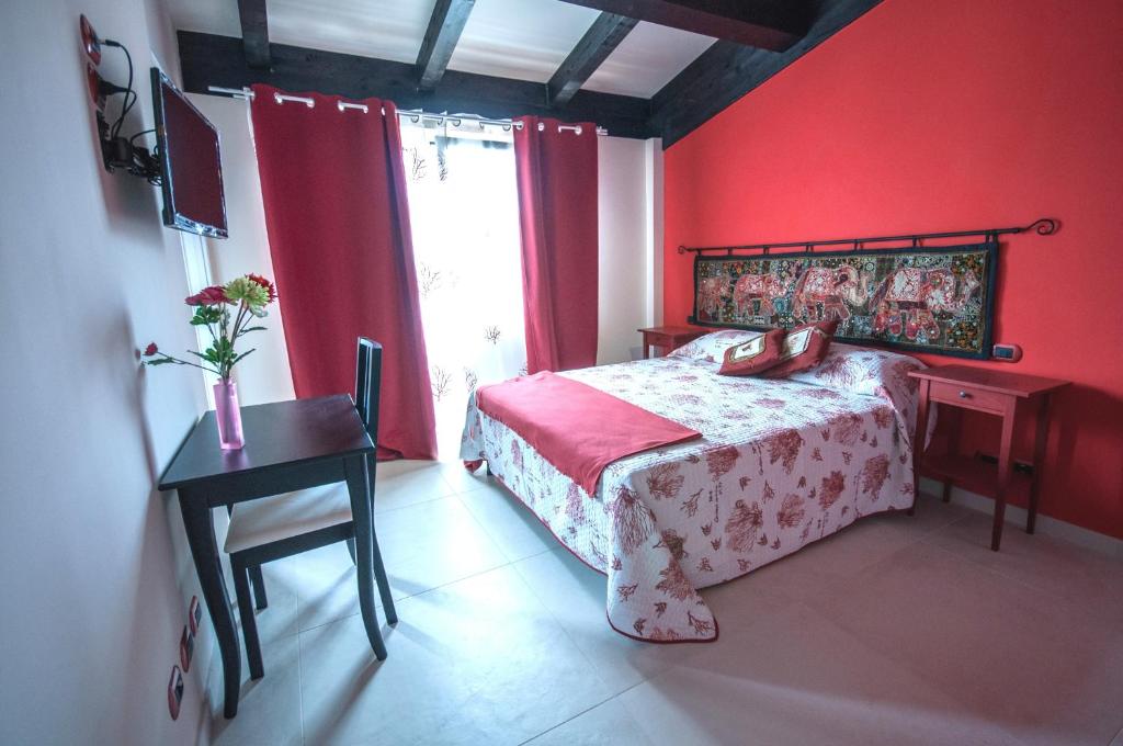 una camera da letto con pareti rosse e un letto con scrivania di B&B I Fiori del Mare ad Agropoli