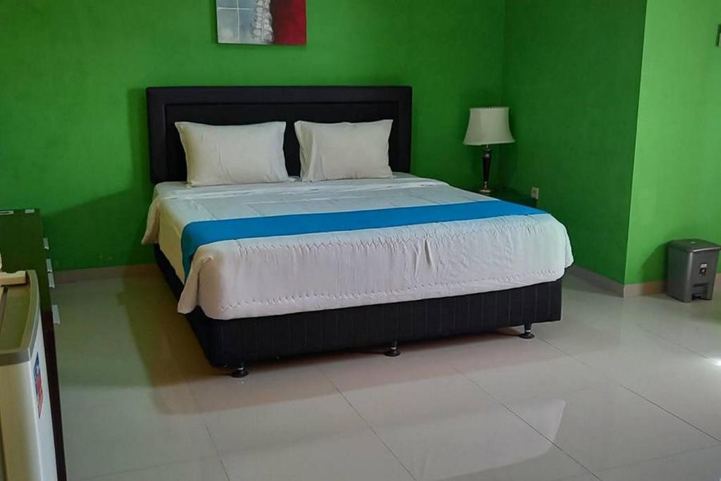 a green bedroom with a large bed in a room at RedDoorz near Bandara Adi Soemarmo Solo in Tjolomadu