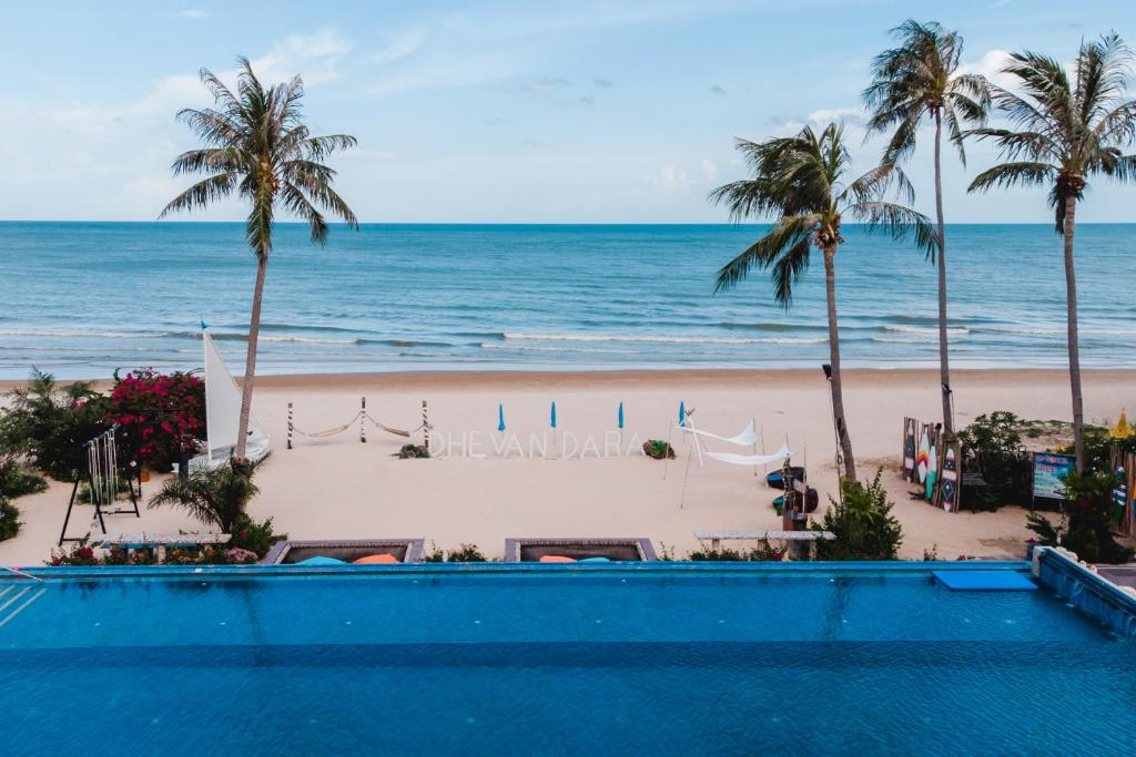 een uitzicht op het strand vanaf het zwembad van het resort bij Dhevan Dara Beach Villa Kuiburi in Kui Buri