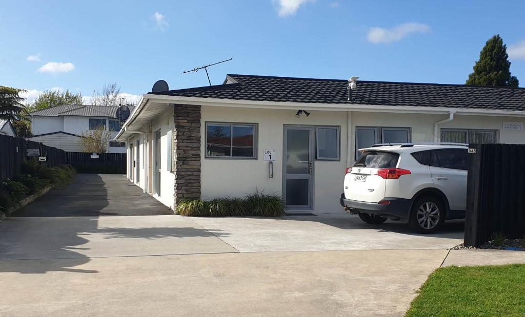 um carro branco estacionado em frente a uma casa em Rose Apartments Central Rotorua- Accommodation & Private Spa em Rotorua