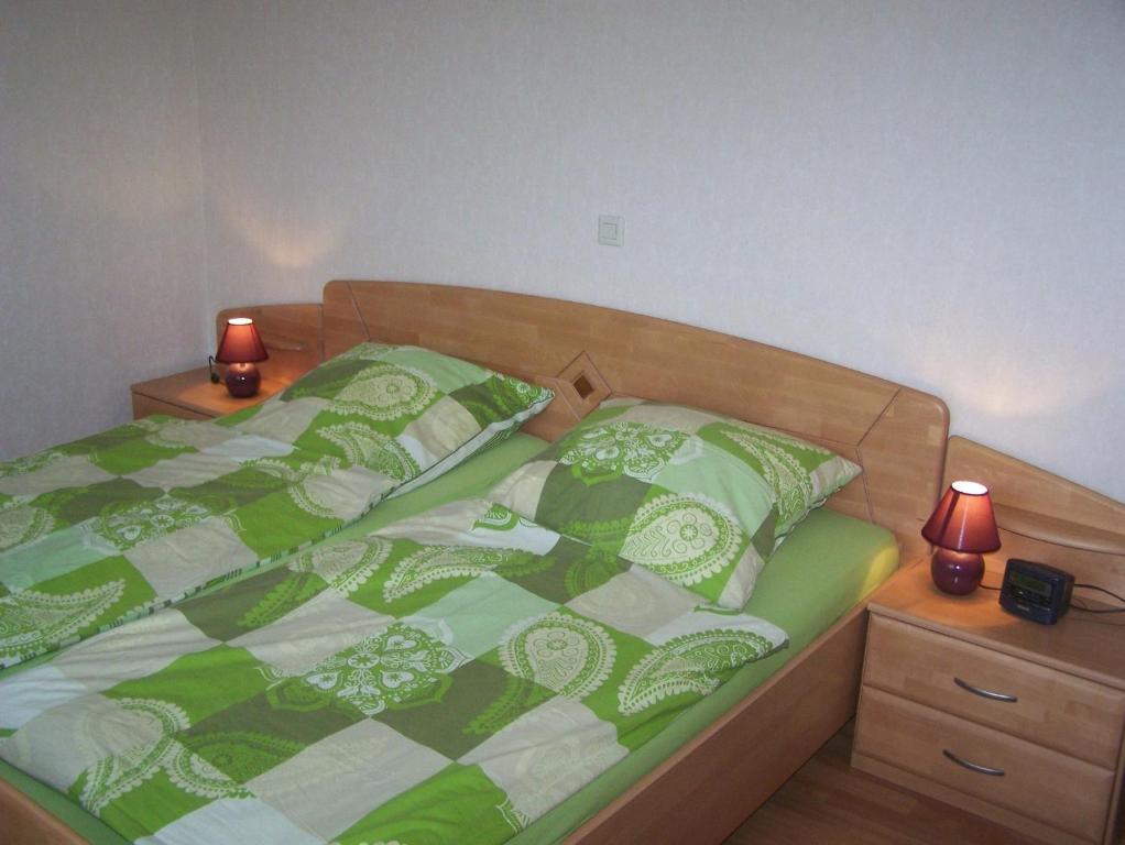 um quarto com uma cama verde e branca com 2 candeeiros em Ferienwohnung Mauer, Wohnung "Ost" em Heede