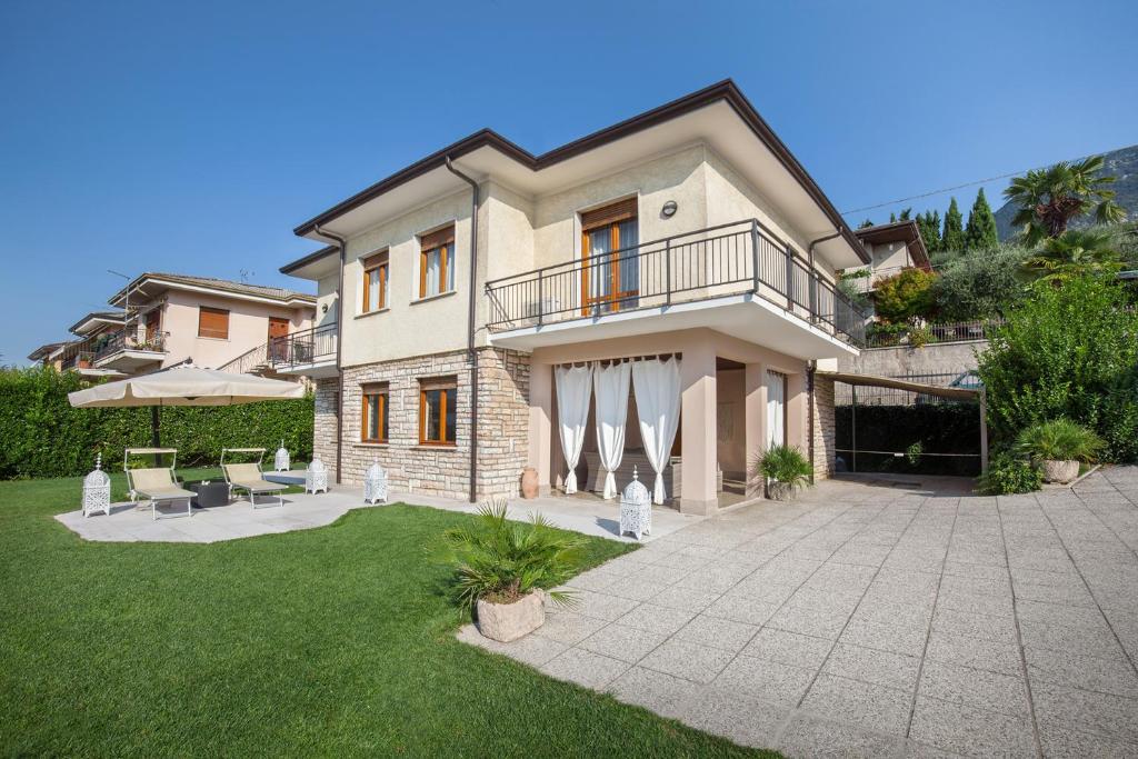 ein großes Haus mit einer Terrasse und einer Liegewiese in der Unterkunft Villa Viola-Comoda villetta a Caprino Veronese in Caprino Veronese