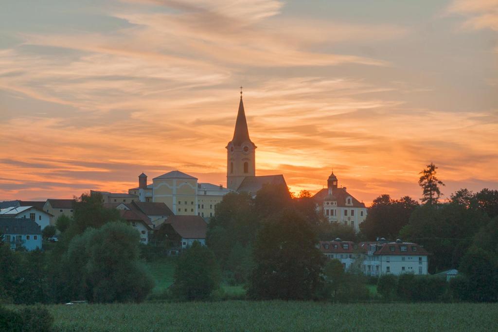 eine Stadt mit einer Kirche mit Sonnenuntergang im Hintergrund in der Unterkunft Ferienwohnung Hagner in Teisendorf