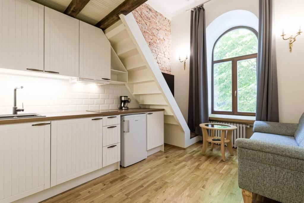 a kitchen with white cabinets and a staircase at City Center Loft Apartment in Tallinn