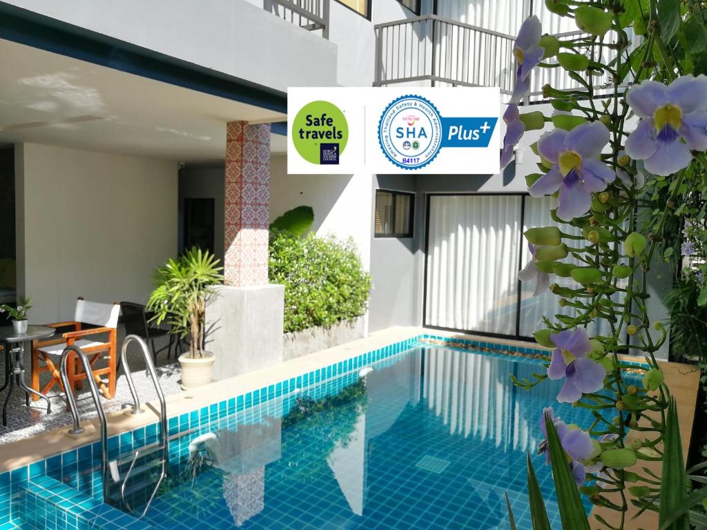a swimming pool next to a building with purple flowers at The Umbrella House - SHA Extra Plus in Kamala Beach