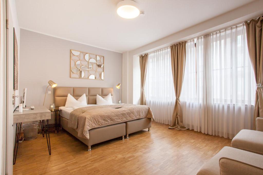 a bedroom with a bed and a desk and windows at TM Hotel Düsseldorf in Düsseldorf