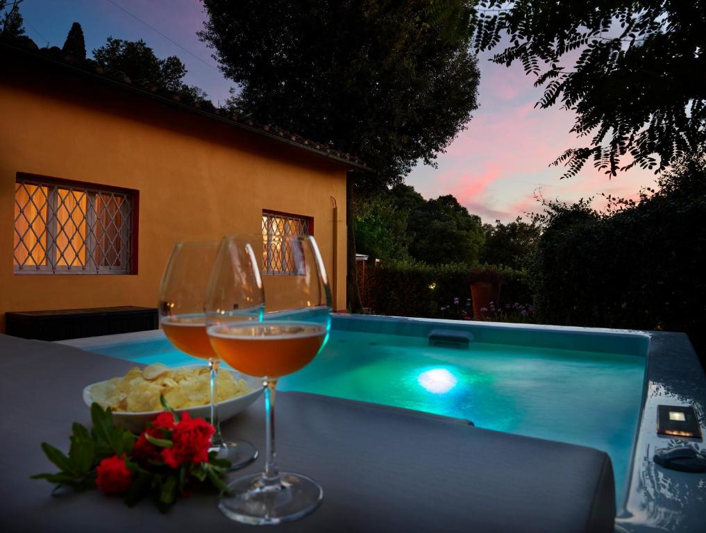 two glasses of wine sitting on a table next to a swimming pool at Cascina Galileo in Florence