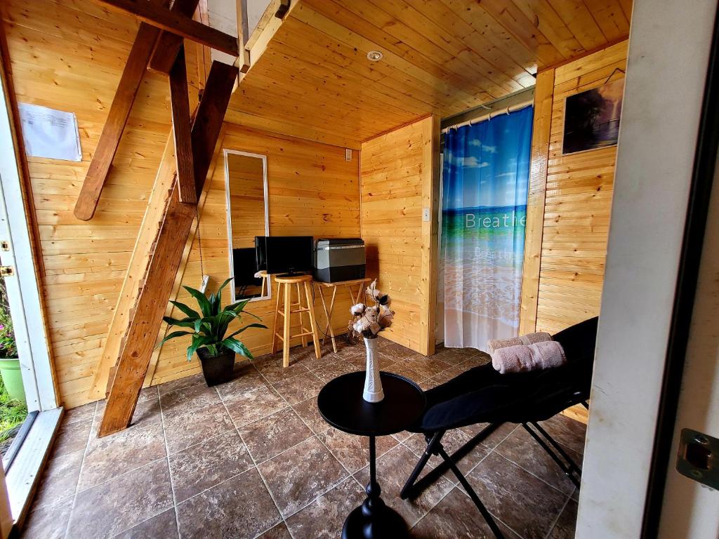 een kamer met houten wanden, een tafel en een televisie bij #1 cabin Tiny house with kitchen equipped with essentials near at the Volcano Park in Pahoa