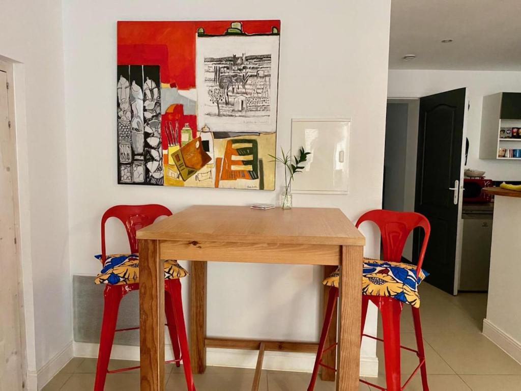 a dining room table with red chairs and a painting at ART'APPART in Narbonne