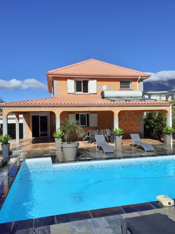 a villa with a swimming pool in front of a house at La perle des montagnes in Cilaos