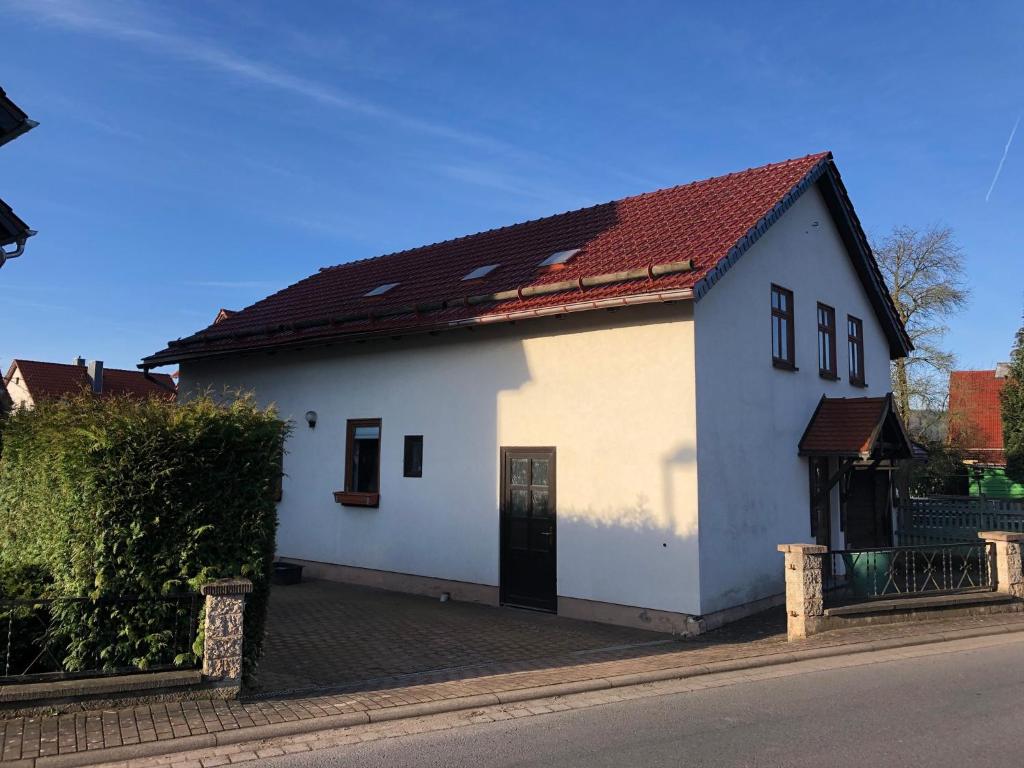 uma casa branca com um telhado vermelho numa rua em Ferienwohnung Familie Tröger em Floh