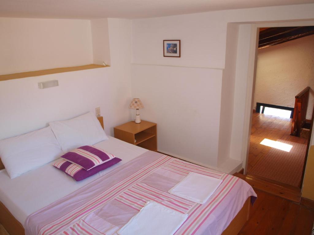 a bedroom with a large white bed with purple pillows at Marina Studios in Symi
