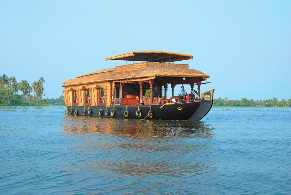 a boat with a roof on the water at Sterling Houseboats Lake Palace, Alleppey in Alleppey