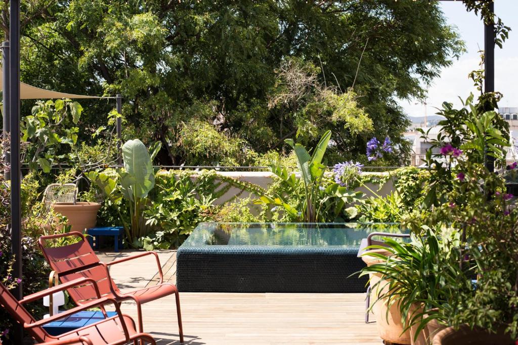 バルセロナにあるHotel Neri – Relais & Chateauxの庭園内のプール(椅子、植物付)