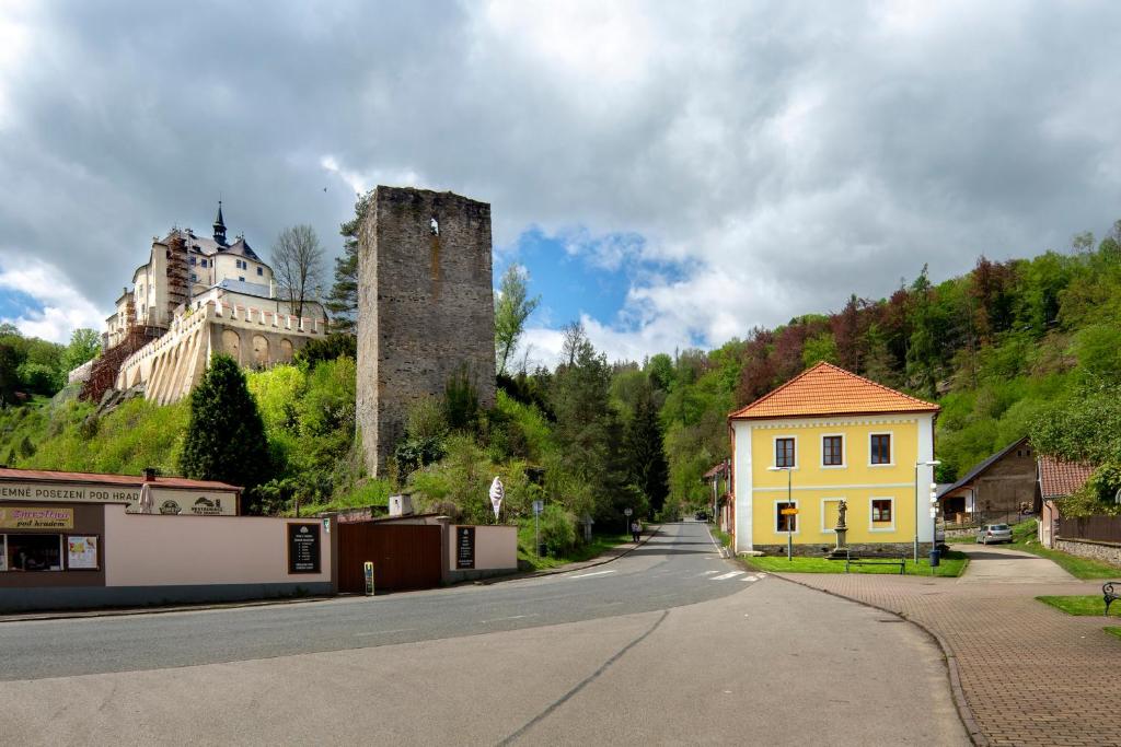 a street with a yellow house and a castle at Apartmány Český Šternberk in Český Šternberk
