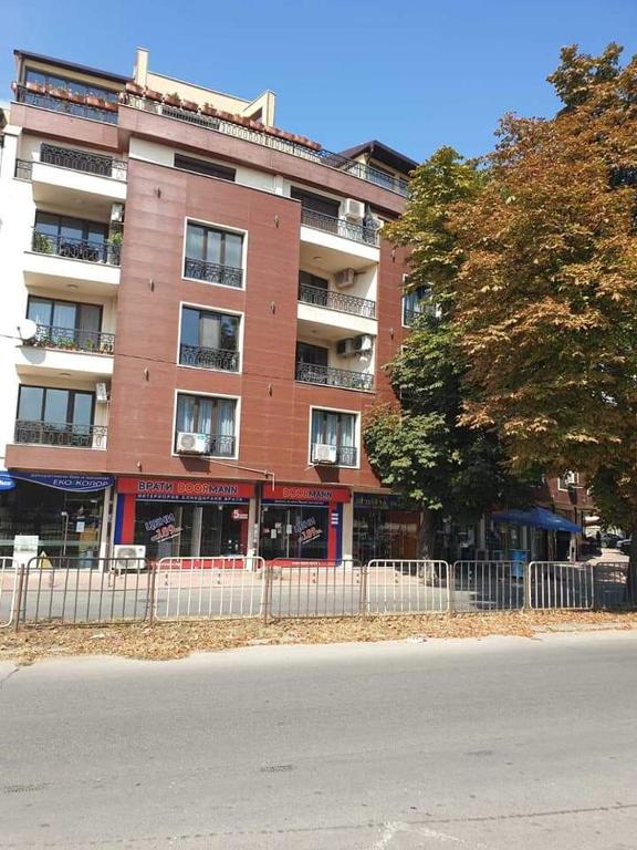 a tall red building with a fence in front of it at Апартамент Quattro in Dobrich