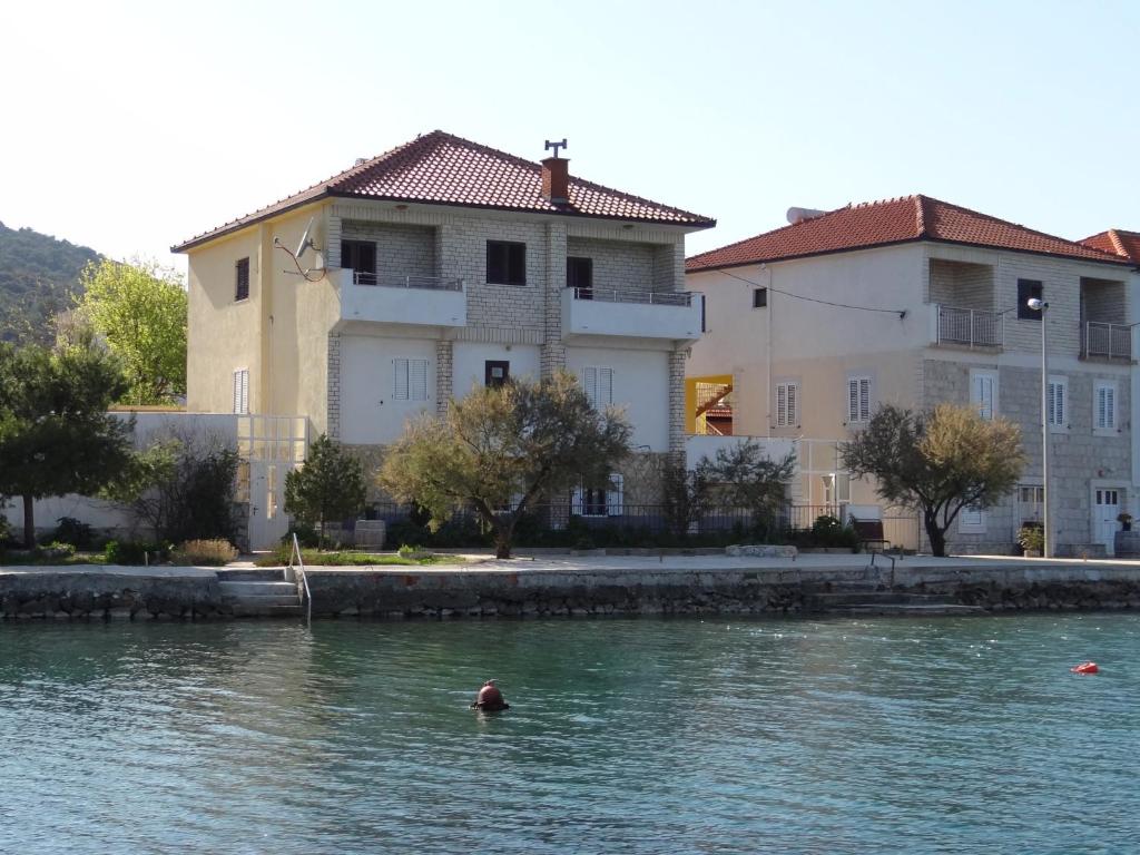 a person swimming in the water in front of buildings at Apartments Babin in Vinišće