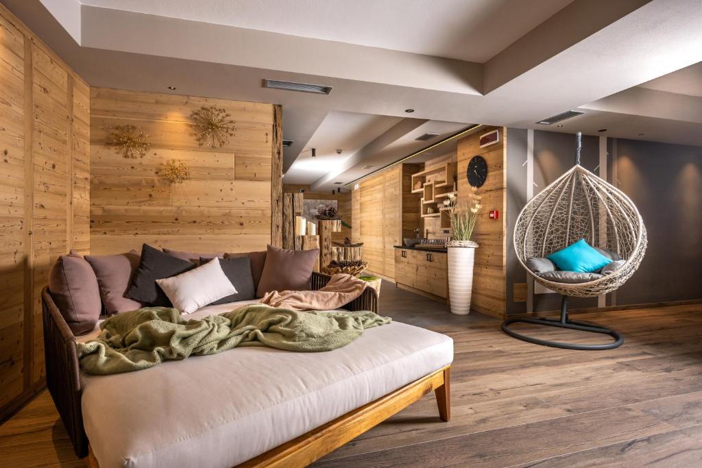 カンピテッロ・ディ・ファッサにあるCesa Edelweiss Living & Spaのベッドとハンギングチェア付きの部屋
