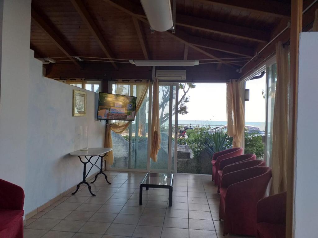 sala de estar con sillas, TV y ventanas en Room in BB - Quadruple room in Pineto - sea view, en Pineto