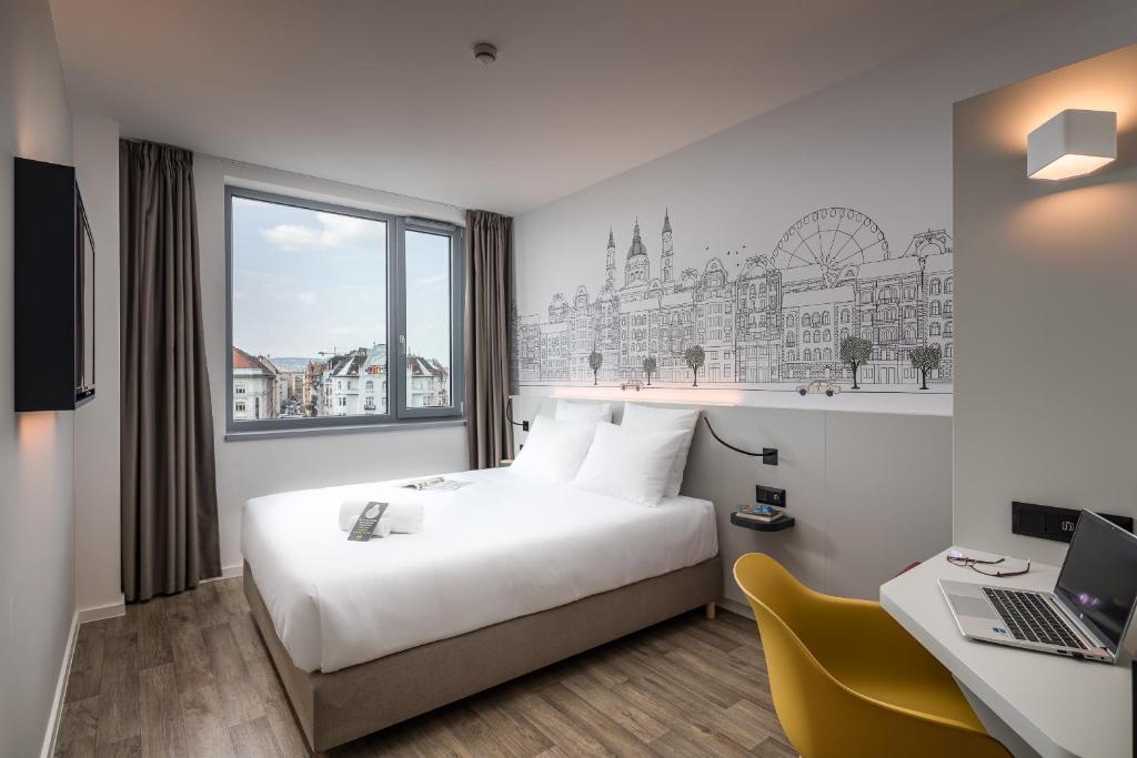 um quarto de hotel com uma cama e uma secretária com um computador portátil em B&B Hotel Budapest City em Budapeste