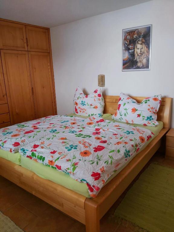łóżko z kwiatową kołdrą i poduszkami w obiekcie Appartment am Egghof w mieście Oberperfuss