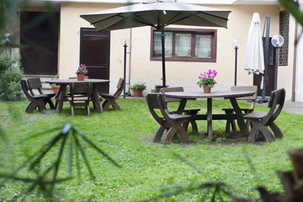two picnic tables and chairs with an umbrella in a yard at Villa Altieri in Albano Laziale