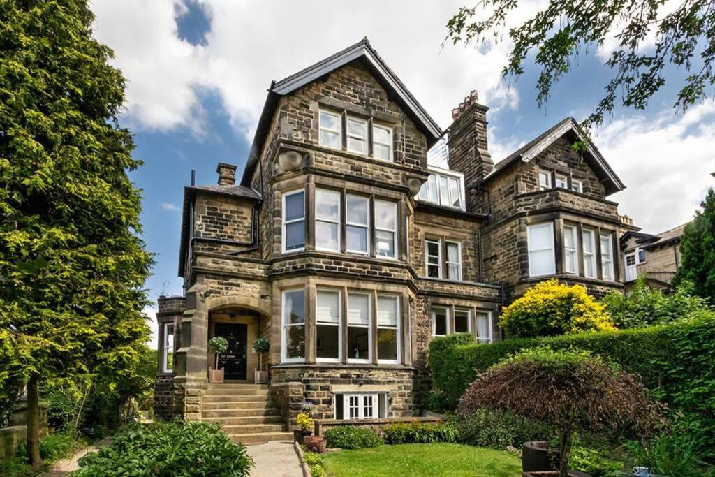 an old stone house with windows and bushes at Central Harrogate townhouse apartment with parking in Harrogate