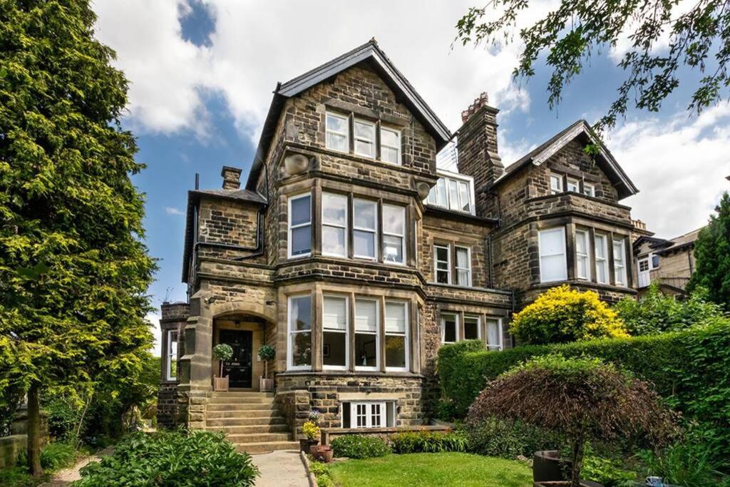 uma antiga casa de pedra com janelas e arbustos em Central Harrogate townhouse apartment with parking em Harrogate